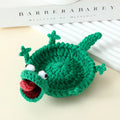 Bright green crochet lizard coaster with googly eyes under a mug